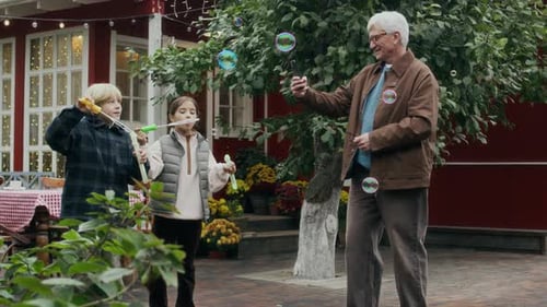 Grandfather Enjoying Precious Moments with Kids Blowing Bubbles in Garden