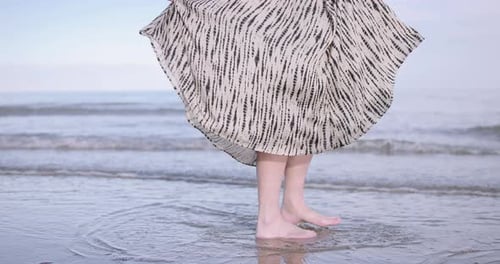 Young adult woman swirling in dress on the beach at sunset