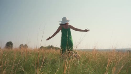 Young Woman Dancing Joyfully in Open Grassy Field Under Blue Sky