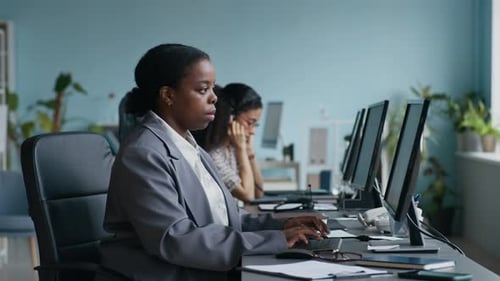Young Elegant Female Operator Typing, Then Looking at Camera and Smiling