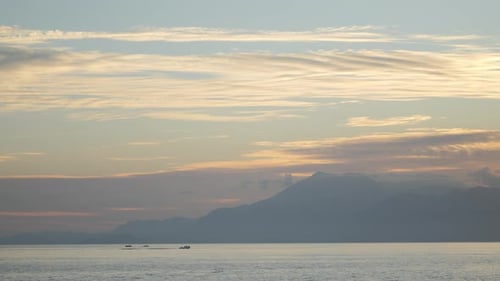 Fishing Boat in the Open Sea Sails Toward the Mountains and Into the Sunset