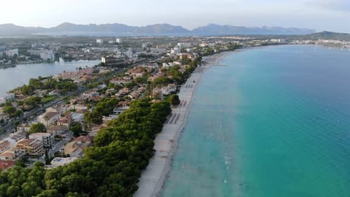 Spain- Aerial footage of the beautiful town and sun loungers arranged near the beach.