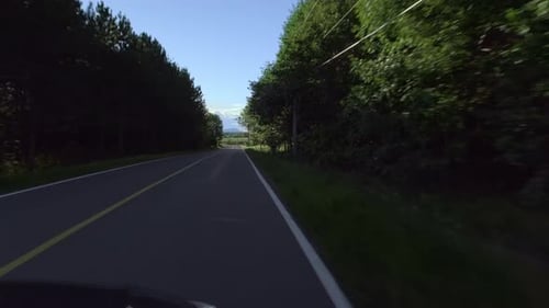 Car driving in the shade of a quiet countryside road