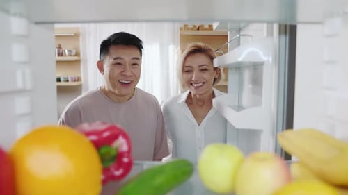 Couple Looks into Fridge, Laughs in Kitchen