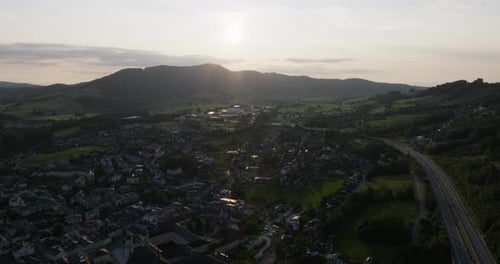 Sunset Over A Town Amidst Mountains And Greenery