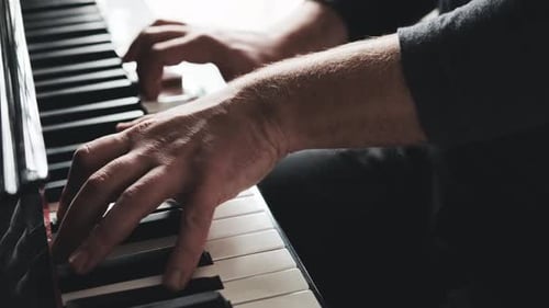Hands Play Piano Keys in a Dark Room