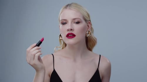 Glamorous Woman Applies Red Lipstick in Studio