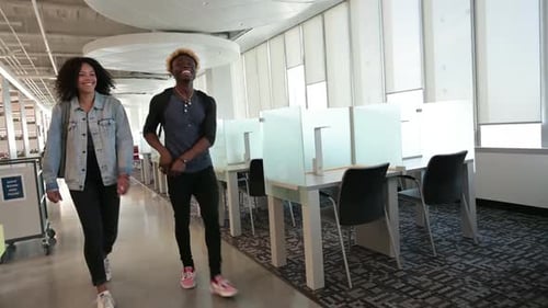 Two Students Walking in Modern Library Talking 20s