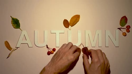 Arranging Autumn Leaves around Wooden Lettering