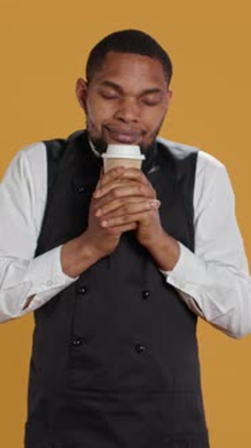 Vertical Video Cheerful Waiter Drinking a Cup of Coffee and Relaxing After Serving Clients