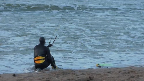 Man engaged in kitesurfing, overcast winter day, high waves, Baltic Sea Karosta beach (Liepaja), slo