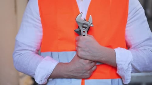 Worker in Safety Vest Holding Adjustable Wrench