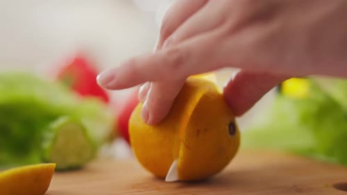 Schneidet eine Zitrone, kocht, Eine junge Hausfrau schneidet in einer heimischen Küche Scheiben einer frischen Zitrone
