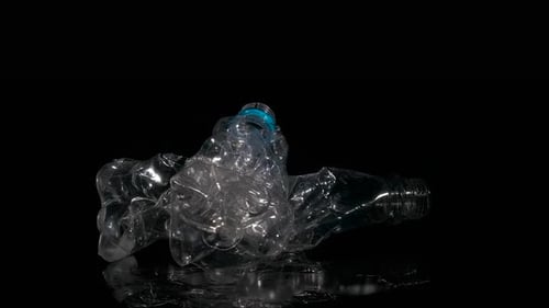 Crushed Plastic Bottle on Reflective Black Surface