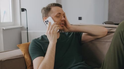 Man Relaxes on Sofa Talking on Cell Phone