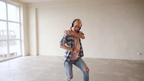 Laughing young man dancer in casual dancing in front of wall. People emotions lifestyle concept. Moc