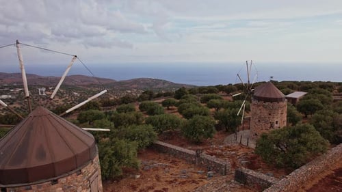 Historic windmills overlook the sea on a scenic hillside in Greece