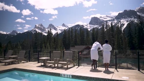 Of Couple in Robes Looking at Mountain View From Pool