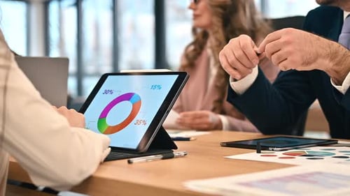 Business meeting in an office, workers discussing business affairs. Tablet with charts and papers on