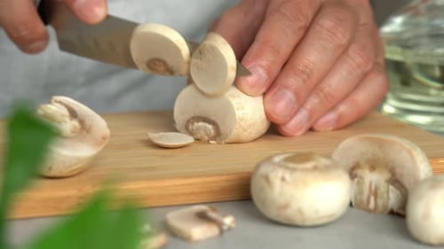 Hands Slicing Mushrooms on a Cutting Board