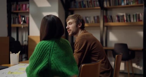 Un étudiant de type masculin communique avec sa collègue féminine et discute de ses idées à une table dans le