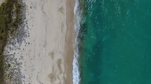 Aerial Top-Down Drone Flies Over Beach, Tilting Up to Reveal Long Coastline, Turquoise Sea,