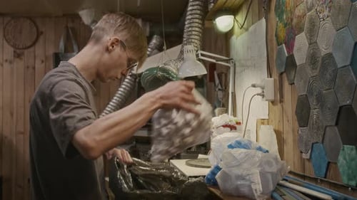 Empleado del taller de reciclaje de plástico recolectando bolsas con tapas de botellas