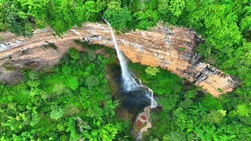 Drone captures majestic waterfall cascading from cliff.