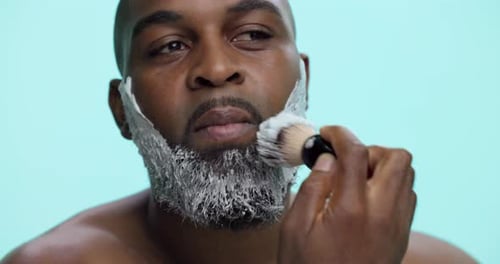 Morning, shaving and man with cream, beard and routine for hygiene in studio and facial treatment