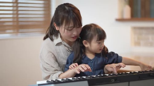 Loving Mother Helping Daughter Learn Piano at Home