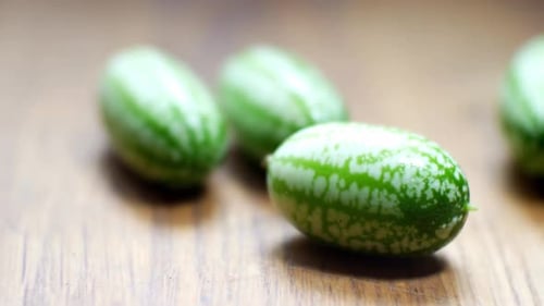 Raw fresh tiny green Mexican cucamelon on wooden kitchen surface selective focus dolly right