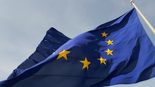Eine Nahaufnahme der im Wind wehenden Flagge der Europäischen Union mit ihrem ikonischen blauen Hintergrund und