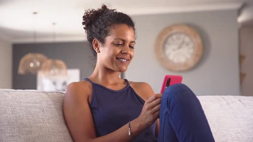 Woman relaxing at home using mobile phone