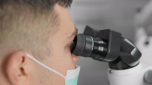 Man Using Microscope in Modern Laboratory Setting