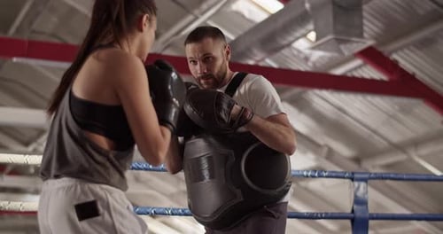 Woman Boxing with Trainer in a Ring