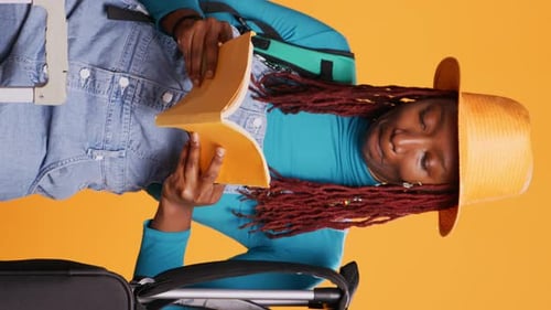 Young Woman Reading Book Sitting Next to Suitcase