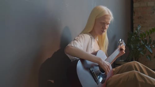 Blonde Woman Plays Acoustic Guitar in Modern Room