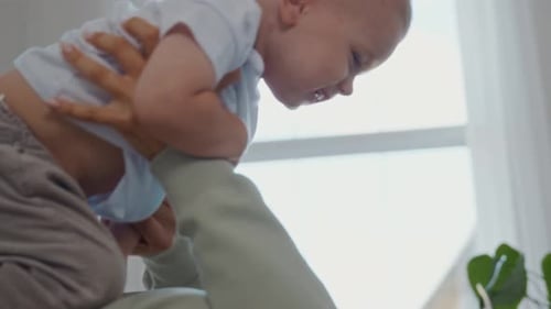 Parent Lifts Baby in Bright, Happy Home Setting