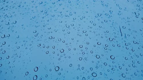 Regentropfen auf Glasfenster, kühle Töne, regnerisches Wetter, abstrakter Hintergrund