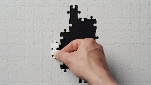 Doigts plaçant un segment de puzzle complétant la structure du puzzle sur un gros plan noir