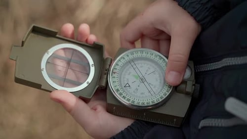 Close-up of a child's hands holding a magnetic compass for navigation.