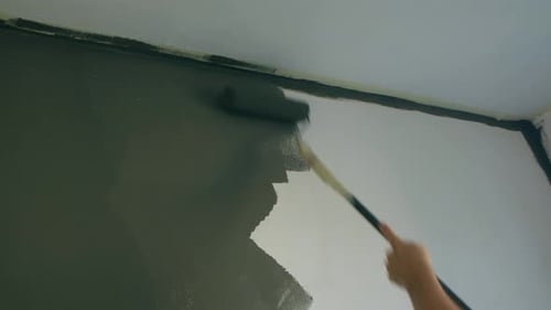 Painting Wall with Grey Paint Roller Indoors