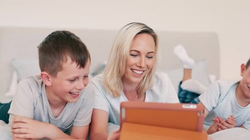 Mother and Sons Enjoying Tablet Together on Bed