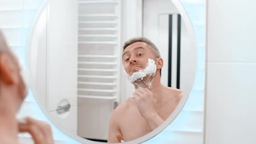 Man, face in mirror and shaving cream, hygiene and grooming with beauty and skincare in morning