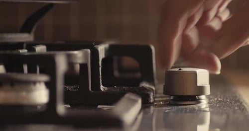 Hand Turns On Gas Stovetop and Puts Pan