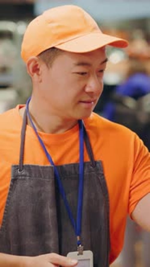 Smiling Store Employee Wearing Apron and Orange Hat