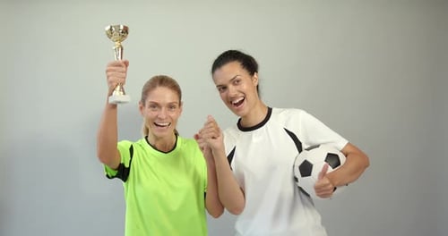 Female Soccer Players Holding Trophy and Soccer Ball