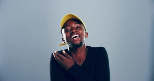 4k video footage of a young man laughing against a grey studio background