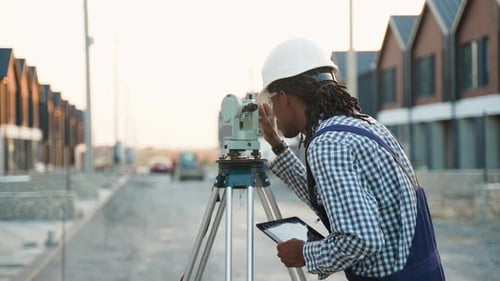 Surveyor Engineer Using Theodolite and Tablet on Construction Site