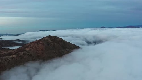 Sommets majestueux émergeant d'une mer de nuages au crépuscule, vue aérienne